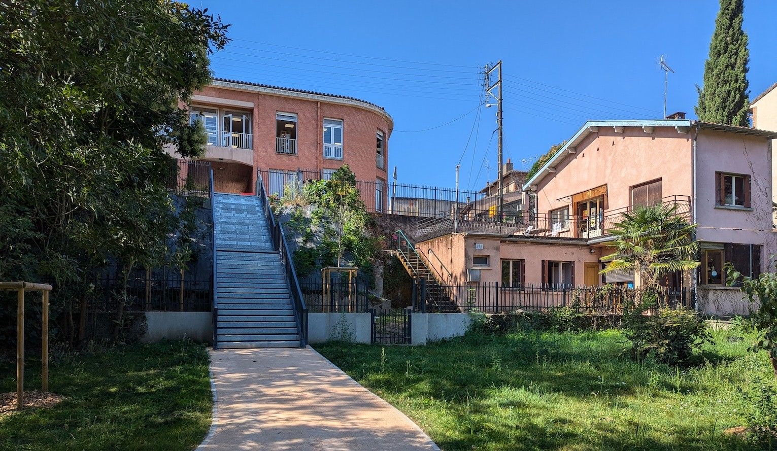Muret (Haute-Garonne), aménagement urbain: un escalier en métal, transparent, assurant la jonction entre une aire de nature et la rue urbaine.